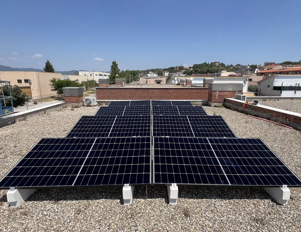 Paneles solares instalados en una cubierta plana con edificios alrededor