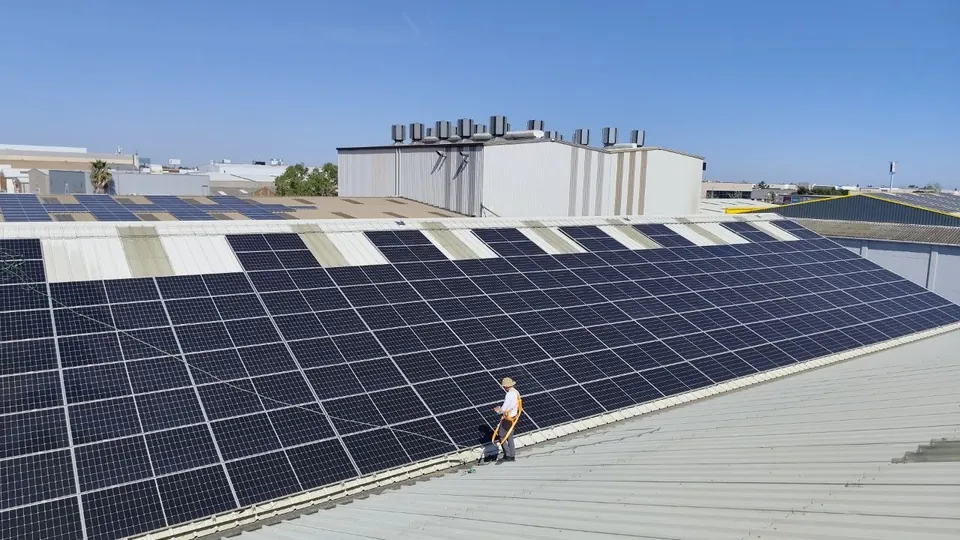 Técnico trabajando sobre paneles solares en una cubierta industrial